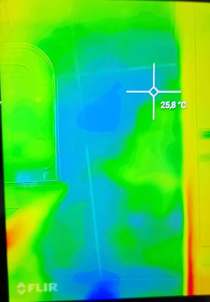 Imagem de câmera termográfica FLIR identificando ponto de umidade e infiltração ativa em parede de banheiro