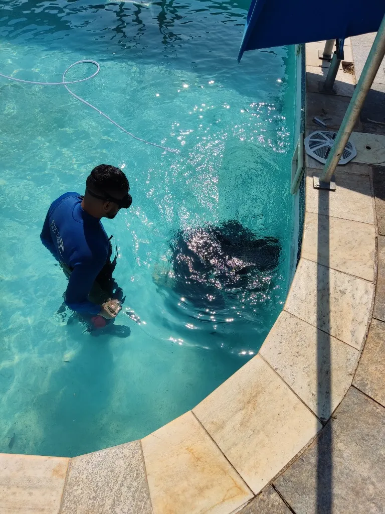 Mergulhador profissional realizando teste de pressão e escuta acústica na tubulação de piscina